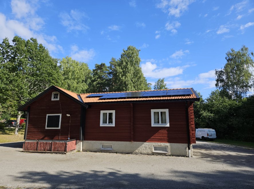 Rött trähus med solceller längs taket hos ett pastorat i Stockholm