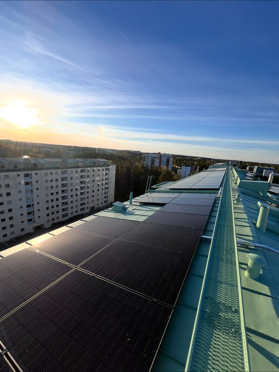 Solcellspaneler på tak med grannhuskets fasad och balkonger nedanför, bostadsrättsförening i Stockholm