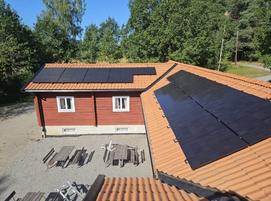 Röda trähus med solceller på taken hos ett pastorat i Stockholm, med Energilösningar Östs servicebil framför