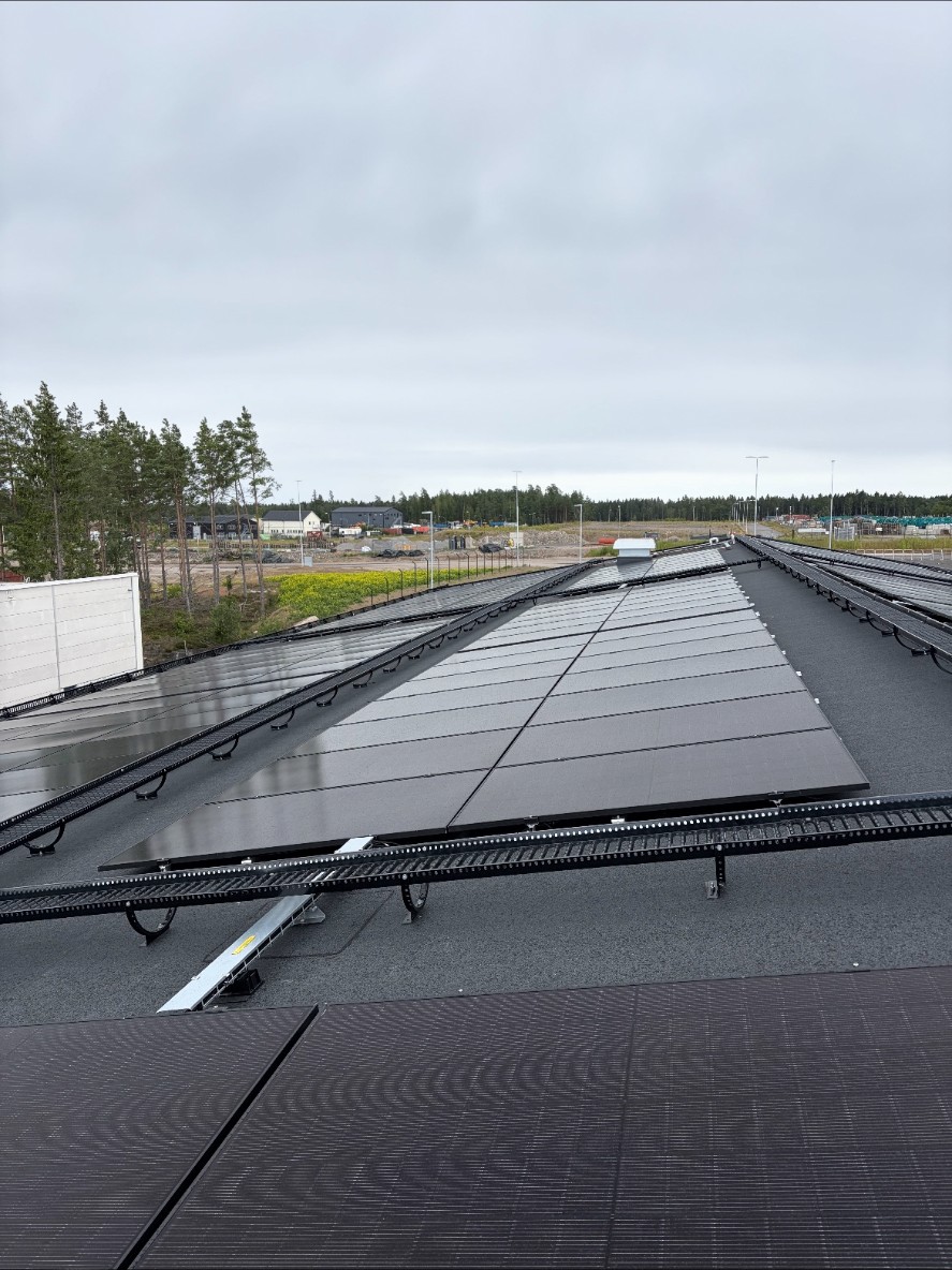 Solcellsanläggning på taket till återvinningscentralen i Nyköping med omgivande natur i bakgrunden